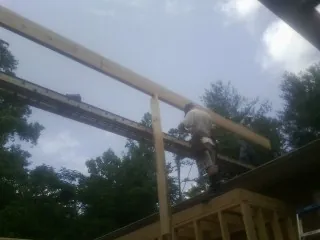 Carpenter setting a ridge beam over a new addition frame — Ice Dam Removal by Roofing Brothers in Pledger