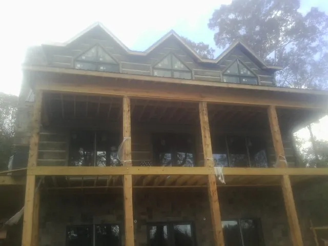 Dormers and porch framing on a large log home under construction — Roof Coating work by our crew in Pledger